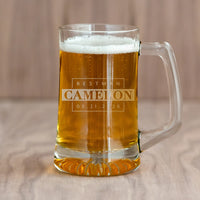Glass mug with beer and engraved text on a wooden surface